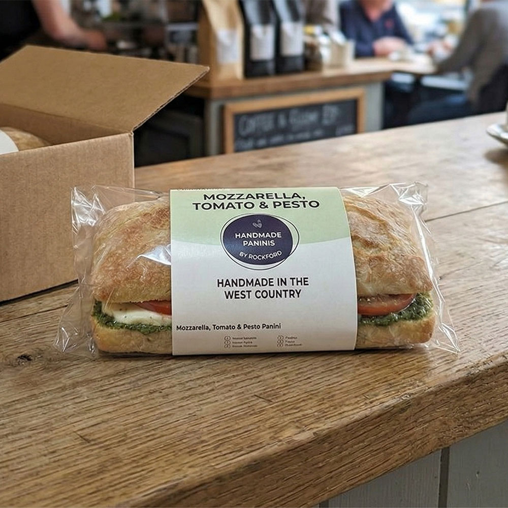 mozzarella, tomato and pesto panini in wrapping on a kitchen counter